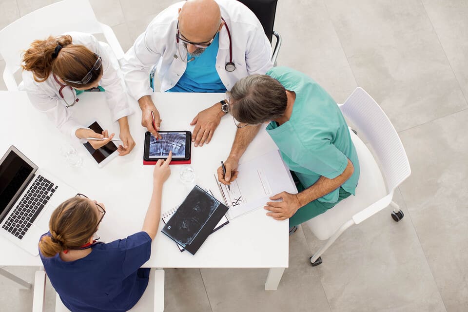 Immagine di quattro dottori che parlano di lavoro ad un tavolo